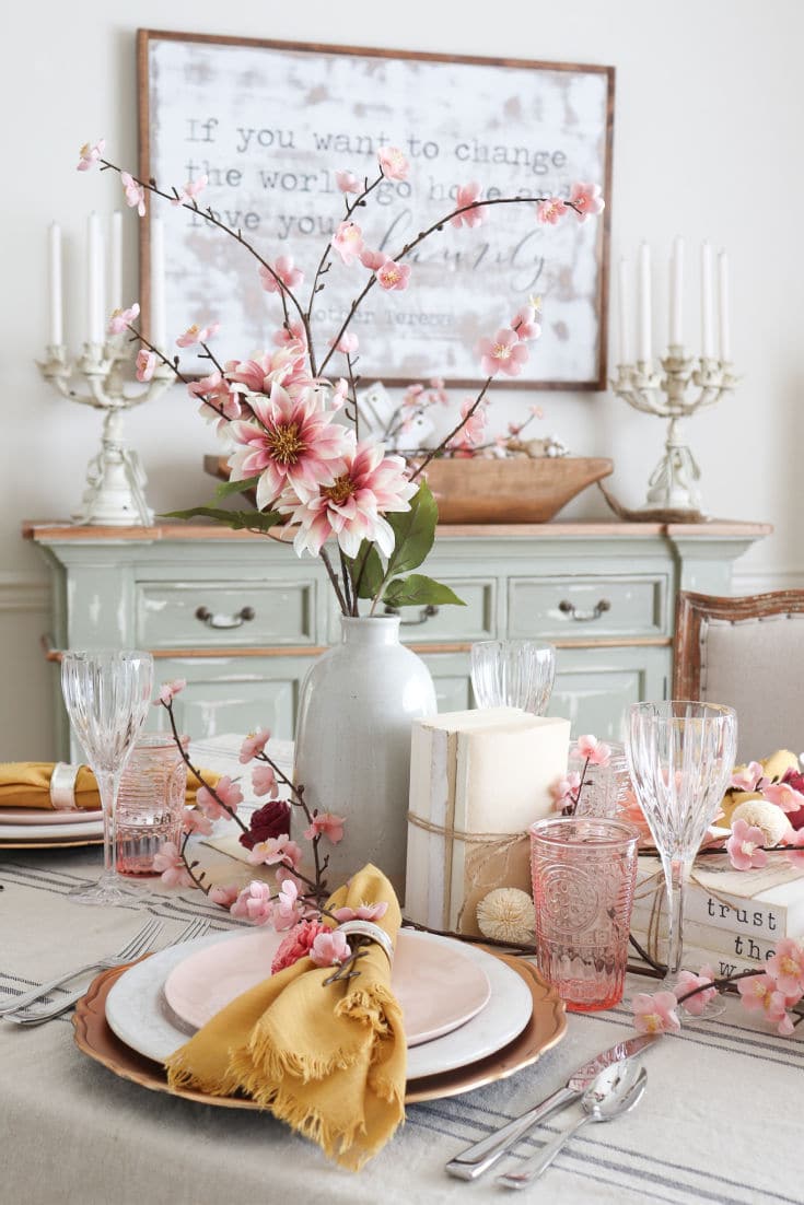 dining room table with pink dinnerware and faux flower centerpiece