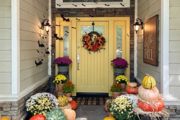 Front door decorated for Halloween with pumpkins and paper bats