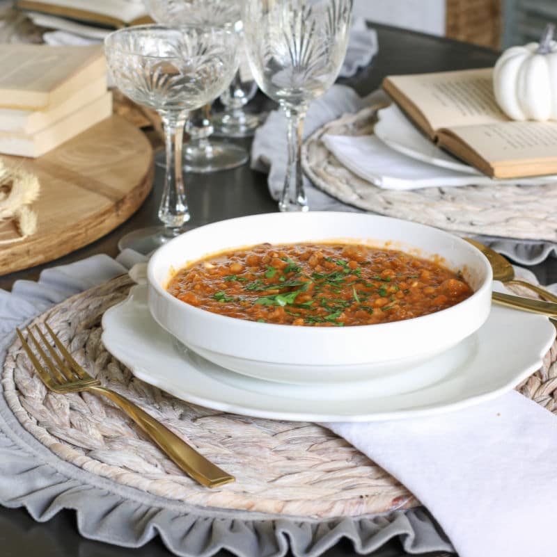 Elegant table setting with crystal glasses and gold flatware and bowl of lentil soup