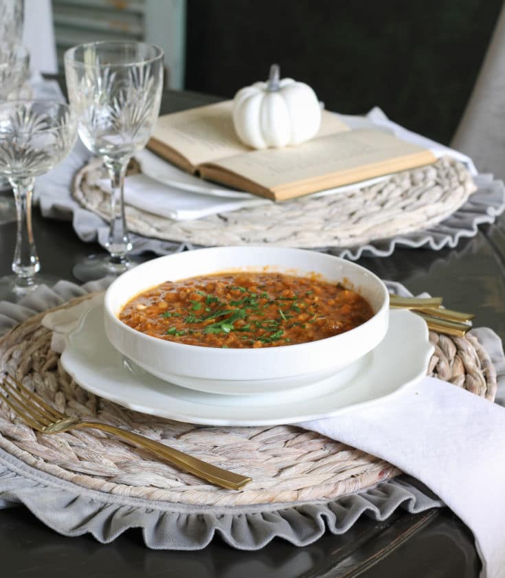 Lentil soup served in white bowl and set on elegant table setting