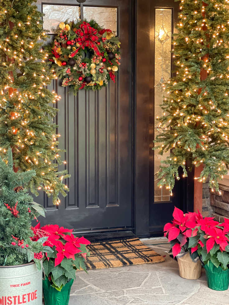 Christmas porch decor includes festive Christmas wreath and Christmas trees with lights