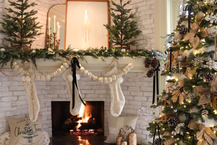 Black gold and white Christmas mantel decor with evergreen trees and wool pompom garland
