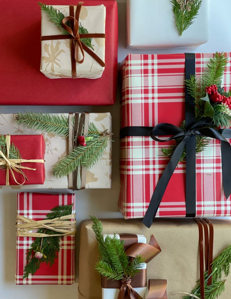 Gift wrapping for Christmas with presents tied up with ribbons and evergreen sprigs