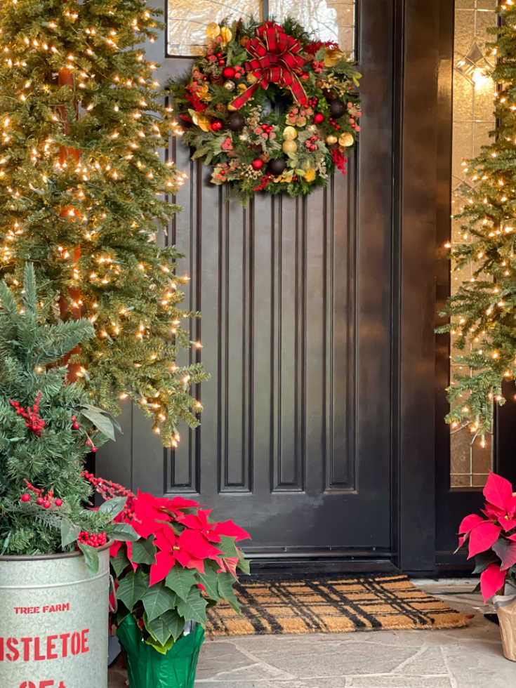 Christmas front porch decor is easy and festive with red poinsettias and Christmas lights
