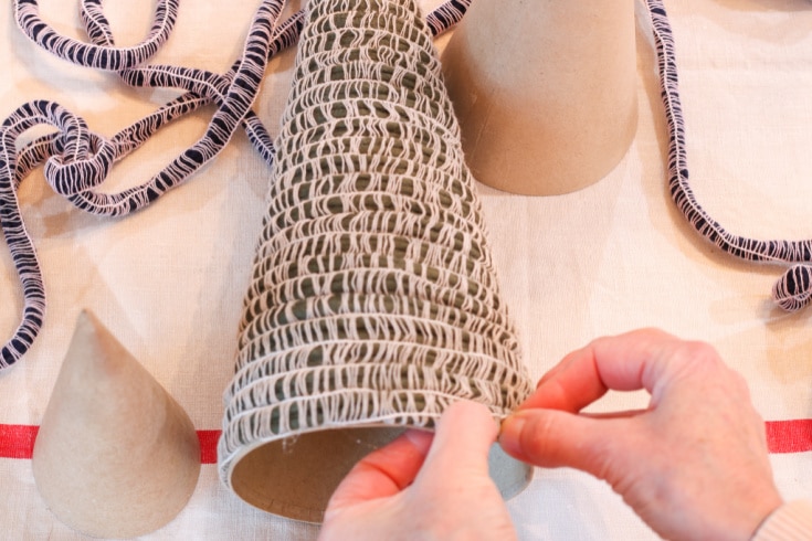 last step in creating mini Christmas tree with mambo yarn is tucking end of yarn behind last row above