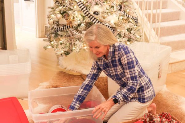 woman organizing Christmas ornaments into clear storage bins