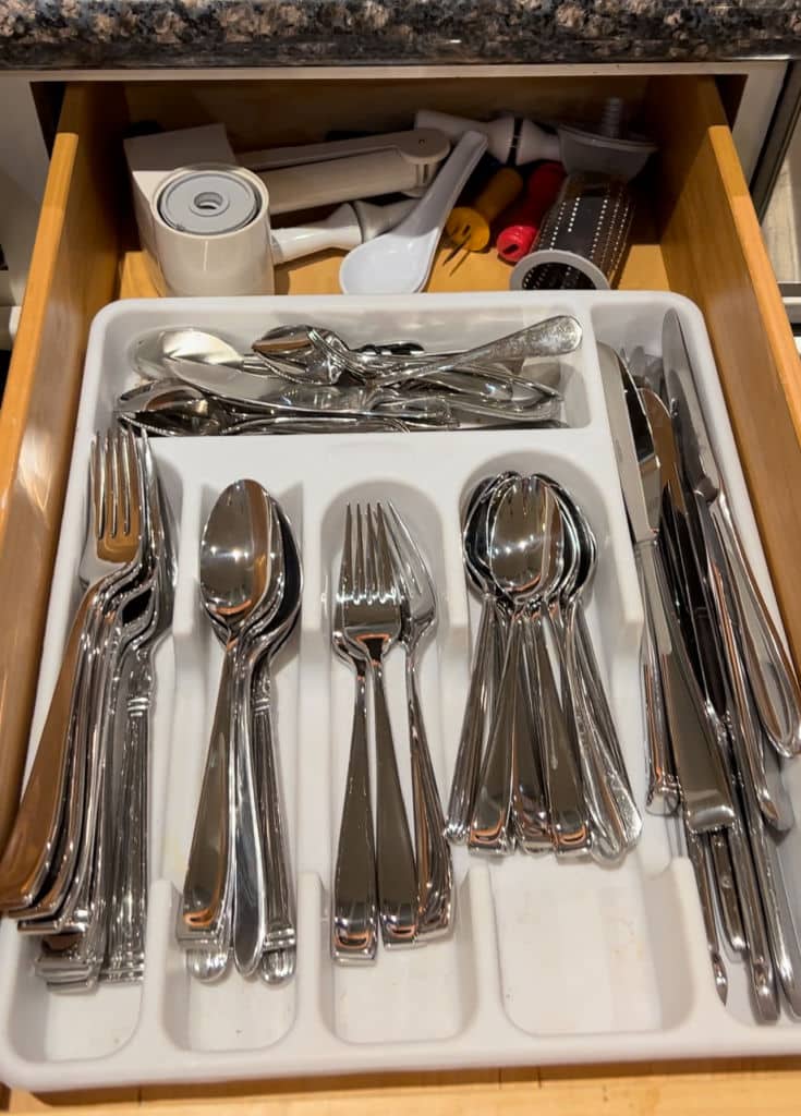 Before photo of silverware drawer shows functionality but lacks beauty in plastic white tray.